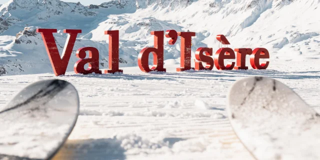 Sciare davanti alle lettere giganti di Val d'Isère in inverno sotto il sole