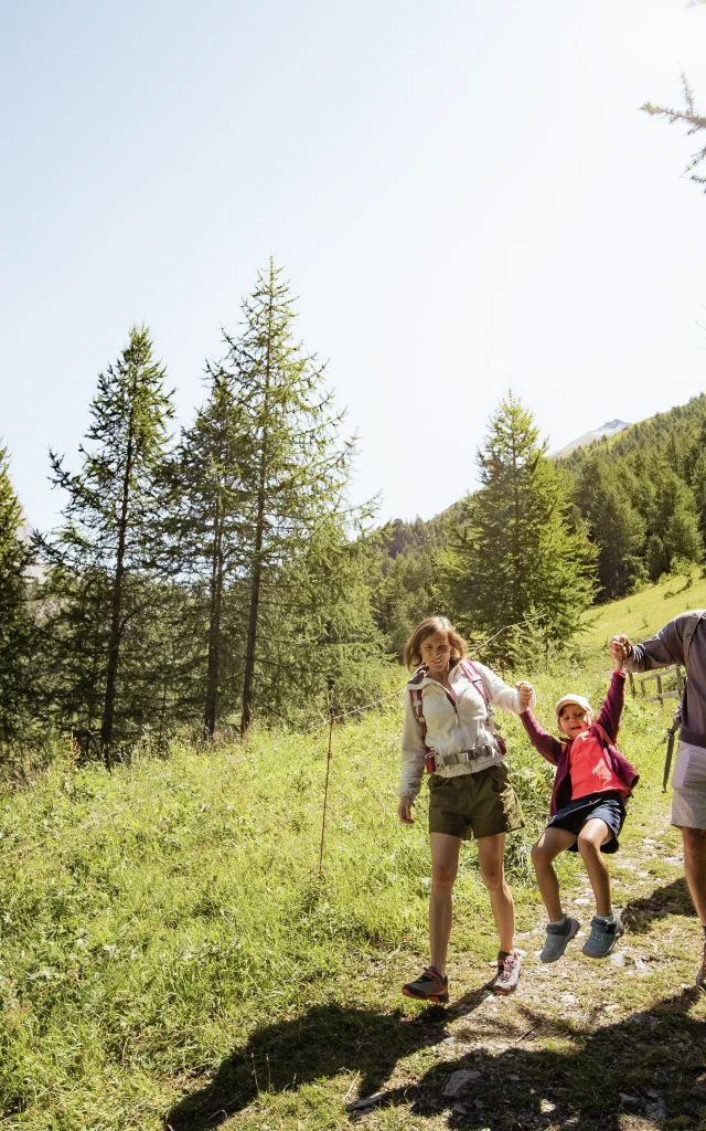 Famille maman, papa et leur enfant en balade dans les forêt autour de Val d'Isère en été