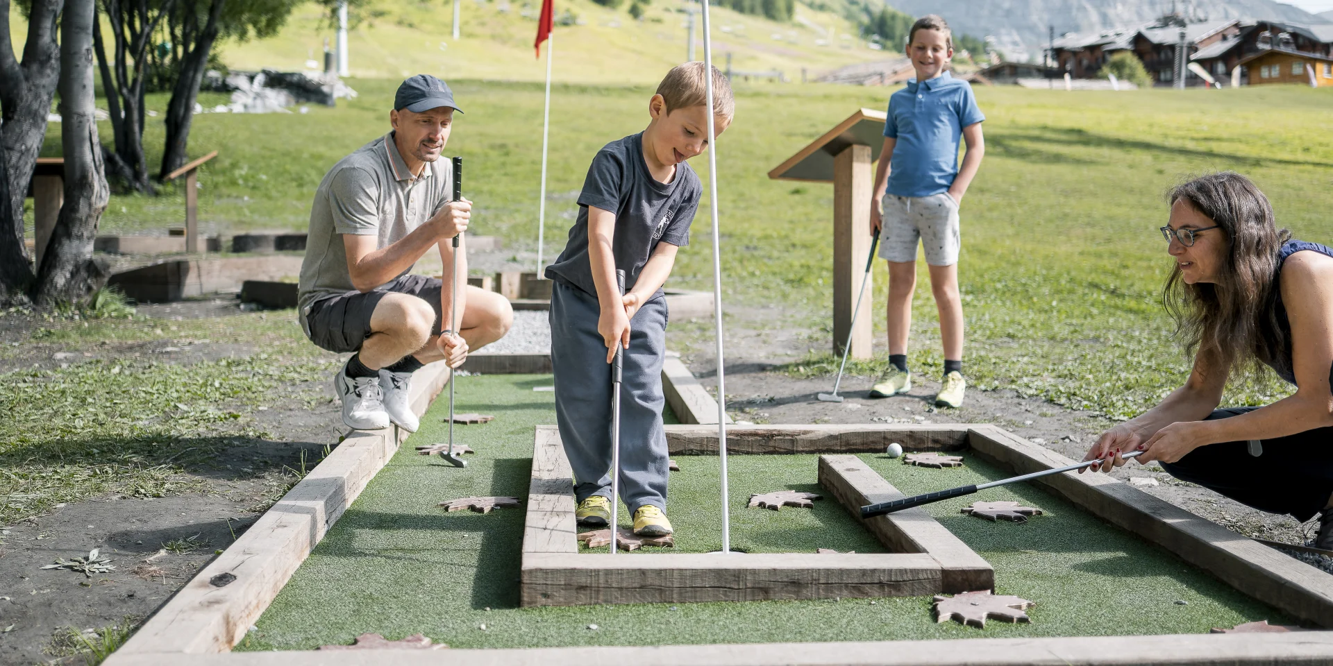 Mini golf en famille (parents et enfant) sur le front de verdure en été à Val d'Isère