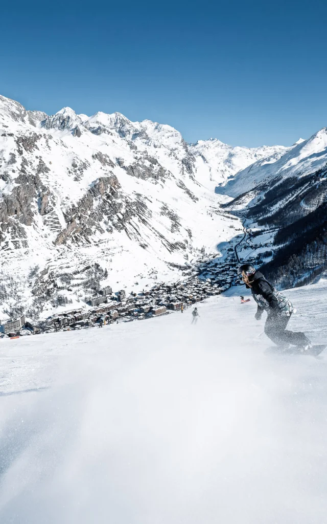 Snowboardeurs avec vue sur le village sur les pistes de Val d'Isère