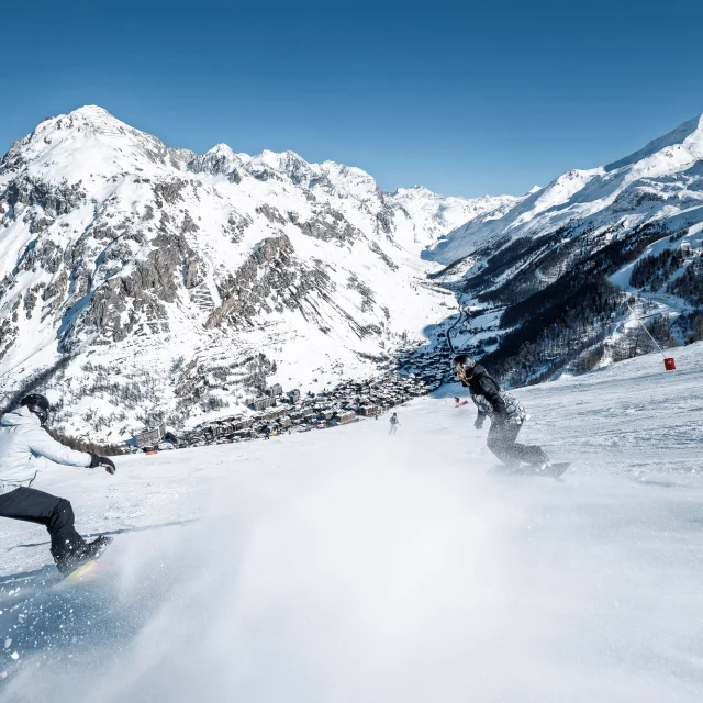 Snowboardeurs avec vue sur le village sur les pistes de Val d'Isère